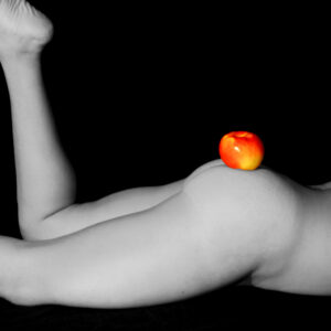 Black and white image of rear nude with colorful apple